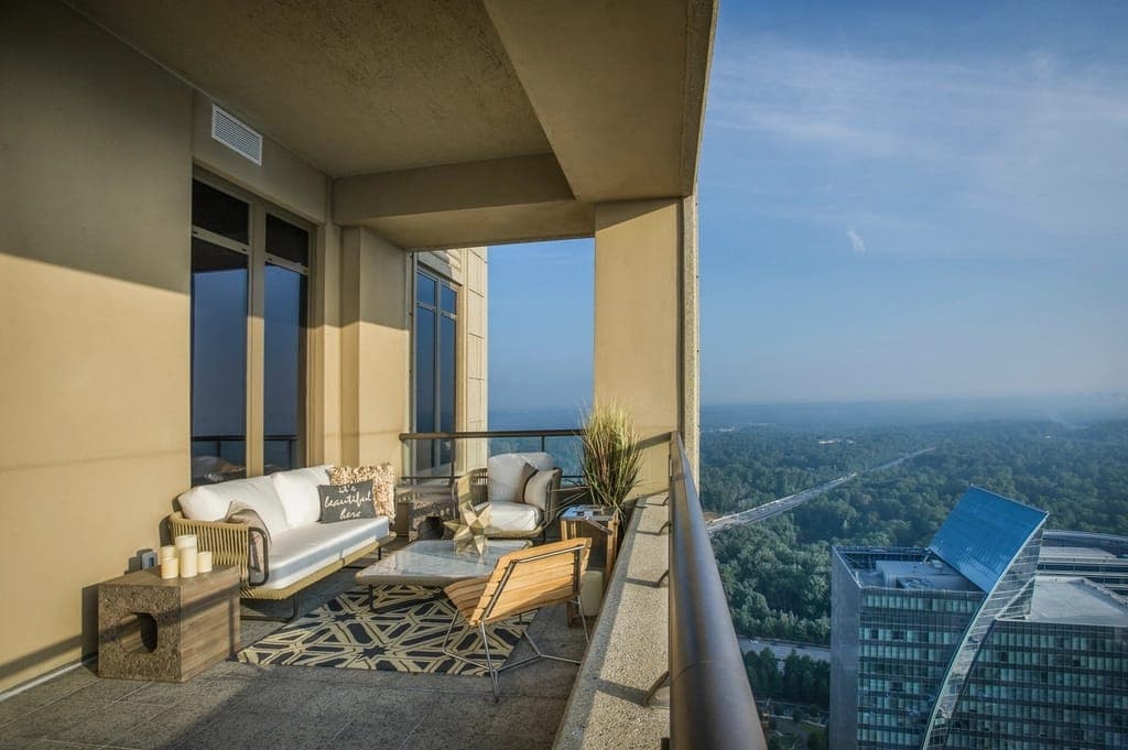 Varanda envidraçada com mesa, poltronas e vista para a cidade