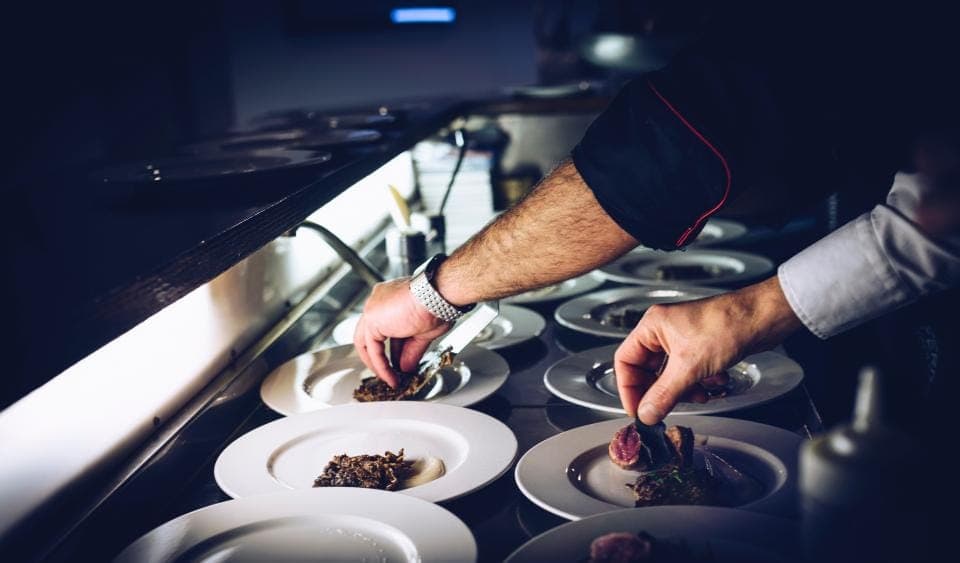 Mãos finalizando pratos na cozinha