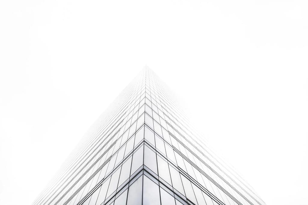 Quina de torre de vidro vista de baixo, sumindo na neblina