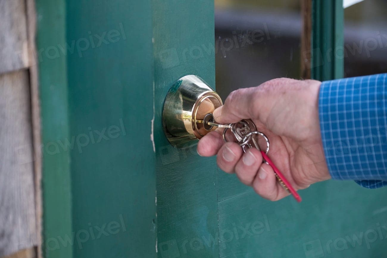 Mão abrindo a porta de um imóvel com um molho de chaves