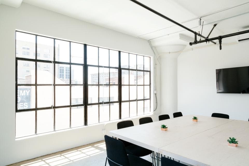 Sala de reunião branca com janelas industriais de ferro