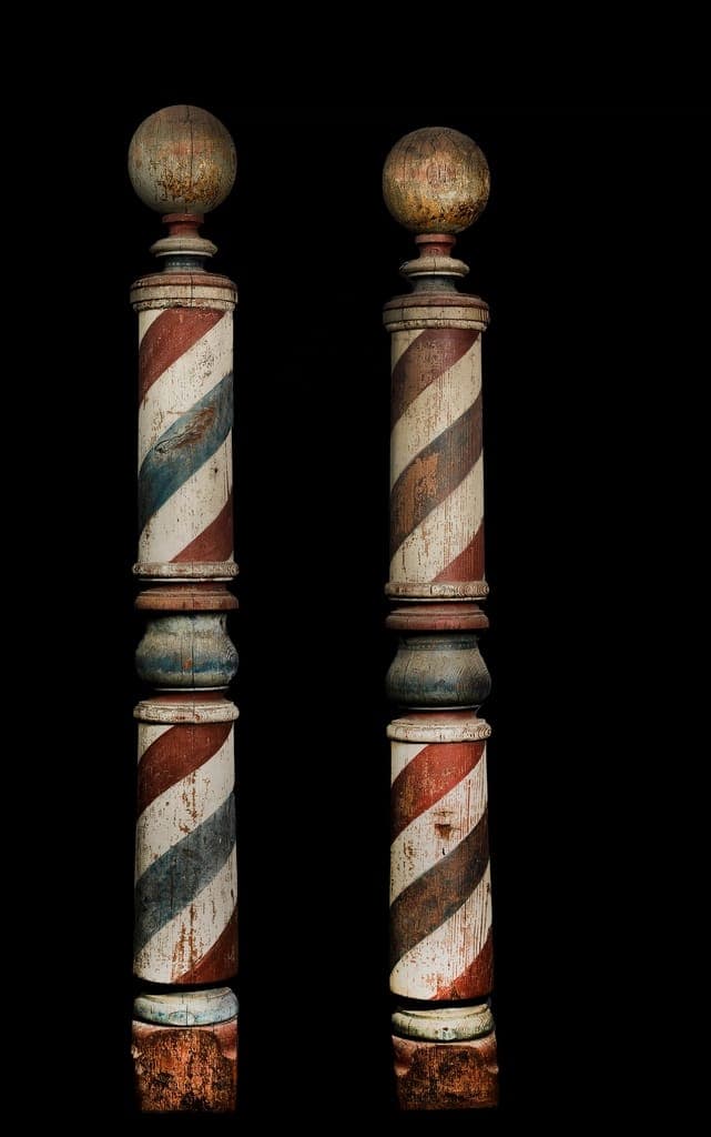 Dois postes de barbeiro antigos, de madeira pintada em espiral